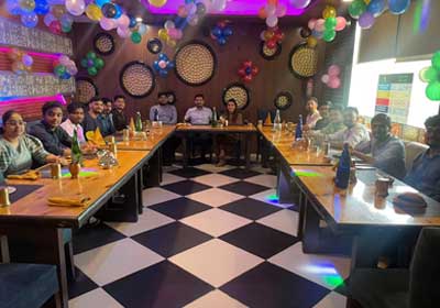 The WhiteWorth team seated around a long table at a celebration dinner decorated with balloons