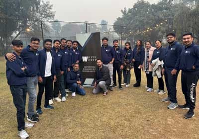 The team gathered around the WhiteWorth banner on a lawn during the annual offsite