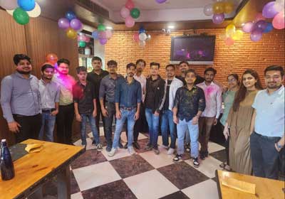 The team celebrating Holi together with colours, under balloon decorations