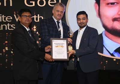 Pratish Goel accepting the Outstanding Leaders certificate and trophy on stage